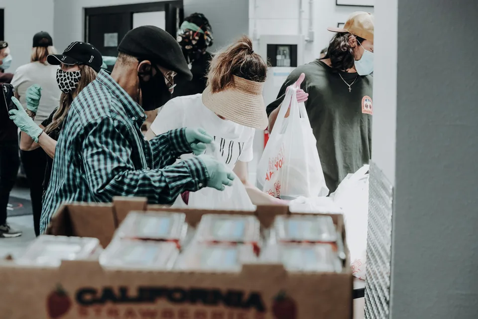 People packing food into bags beside cardboard boxes